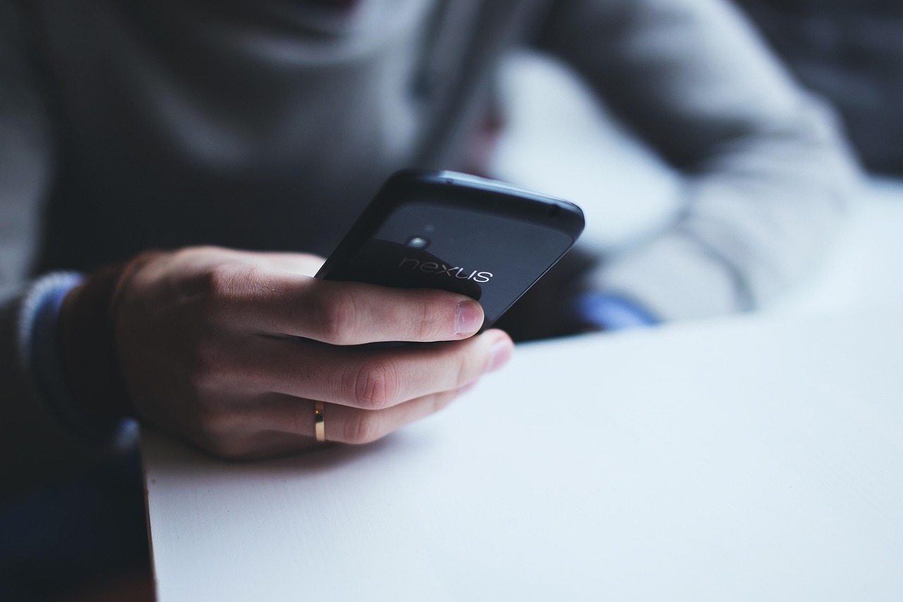 スマートフォンで義実家に電話し墓参りの誘いを断る様子
